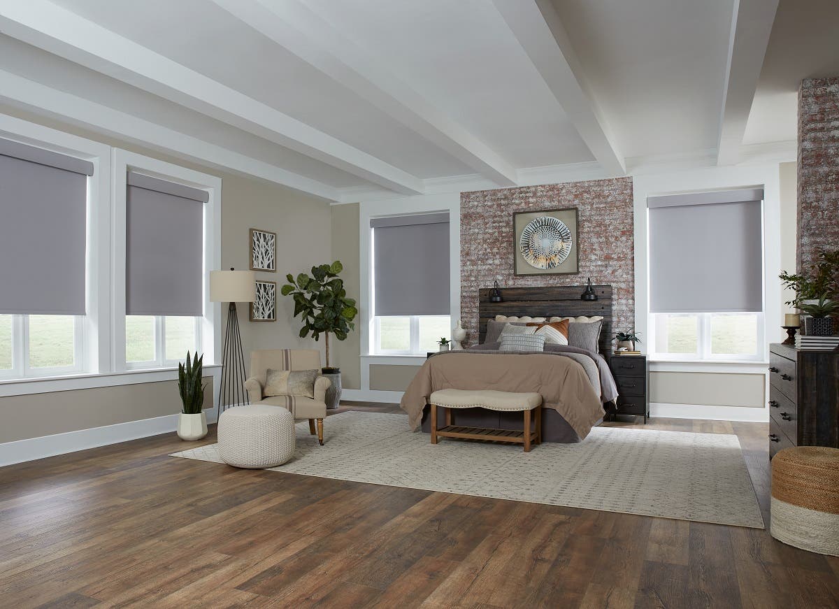 Spacious modern bedroom with light gray motorized roller shades mostly shut